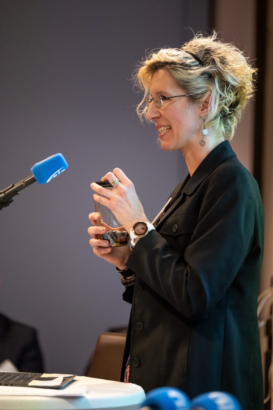 Sabine Finster lächelnd am Rednerpult mit Mikrofon während eines Fachvortrags zur psychischen Gesundheit von Kindern und Jugendlichen
